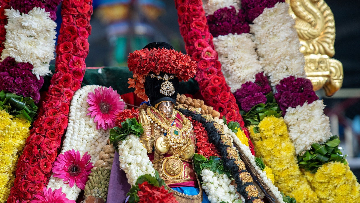 A golden Rama utsava murti buried in rose, jasmine and marigold garlands at a Ram Navami temple procession.