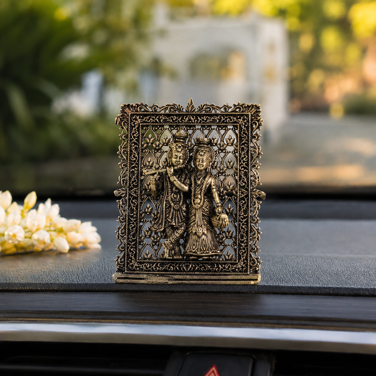 Brass framed Radha Krishna idol placed on a car dashboard