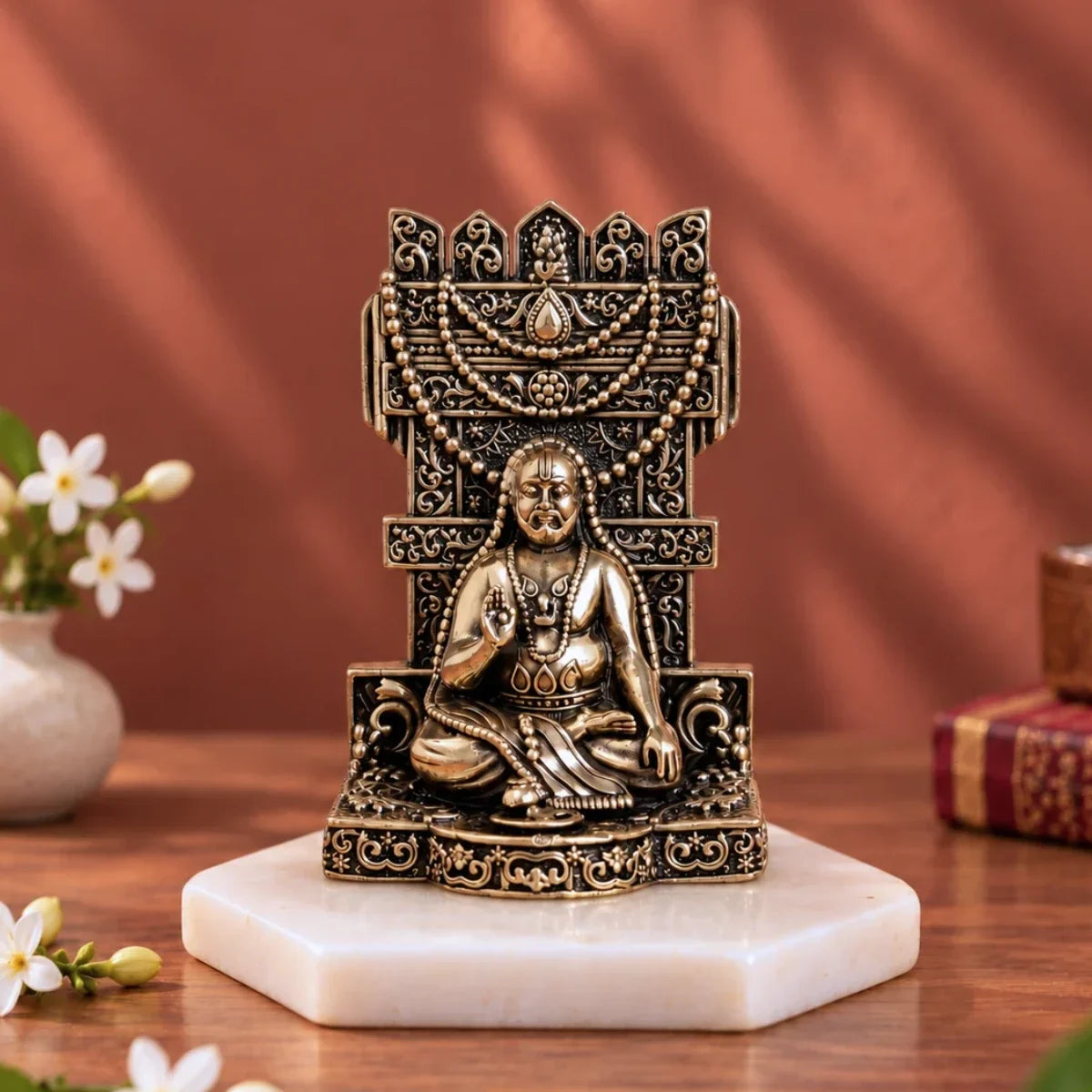 Brass Guru Raghavendra Swamy murti on an ornate carved singhasan, placed on a white marble base