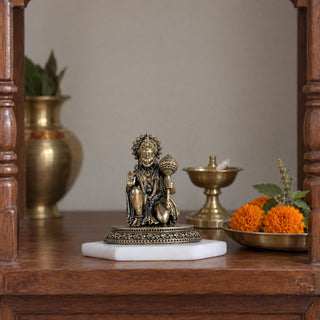 3.5 inch brass kneeling Hanuman idol in abhaya mudra on a marble base in a home mandir beside a brass diya, kalash and marigolds