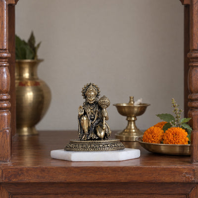 3.5 inch brass kneeling Hanuman idol in abhaya mudra on a marble base in a home mandir beside a brass diya, kalash and marigolds