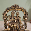 Brass Lakshmi Narayan murti seated beneath a carved arch for home mandir
