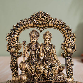 Brass Lakshmi Narayan murti seated beneath a carved arch for home mandir
