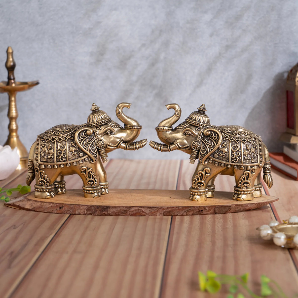 Brass royal elephant pair facing each other with raised trunks, tiered head ornaments and ornate floral saddlework