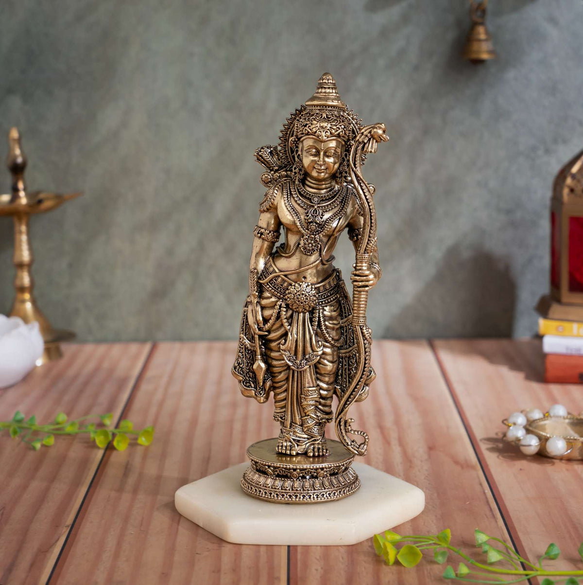 Front view of brass standing Lakshman idol holding a bow and arrow on a carved round pedestal