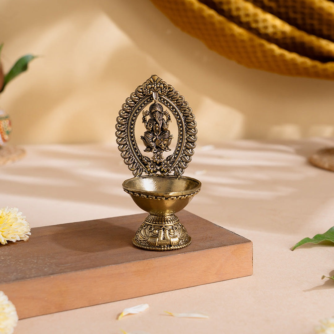 Divine Brass Ganesha Diya with carved Ganesha frame and footed oil bowl on a wooden stand