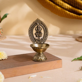 Divine Brass Ganesha Diya with carved Ganesha frame and footed oil bowl on a wooden stand