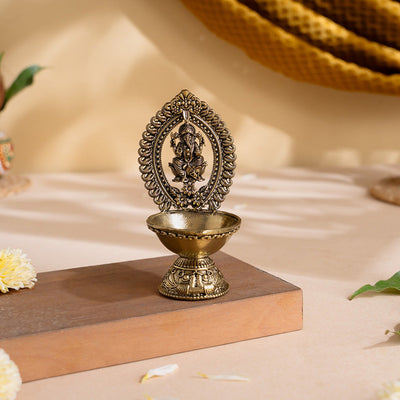 Divine Brass Ganesha Diya with carved Ganesha frame and footed oil bowl on a wooden stand